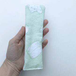 Shows hand holding light green-blue panty liner. It is rectangular, easy to sew and uses a safety pin instead of snaps, which is more secure.